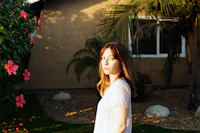 a woman standing in front of a house with a skateboard